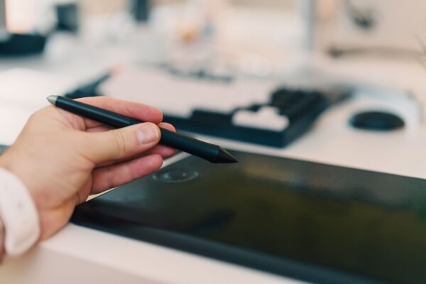 Artista usando caneta stylus em mesa digitalizadora com Clip Studio Paint aberto