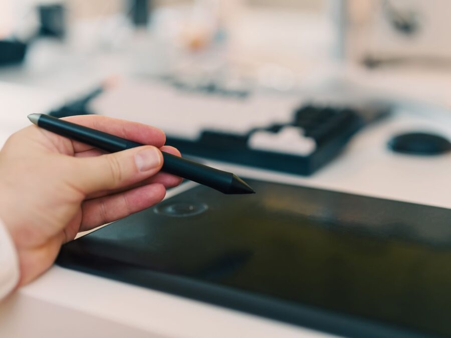 Artista usando caneta stylus em mesa digitalizadora com Clip Studio Paint aberto
